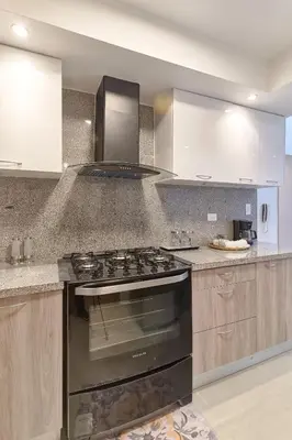 a kitchen with a stove and white cabinets at Dom. Rep. Exclusive 2 bed Apt. Evaristo Morales in Santo Domingo