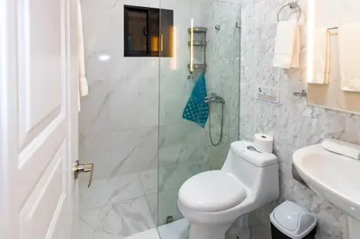 a bathroom with a toilet and a glass shower at Hotel Señorial in Santo Domingo
