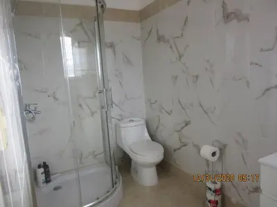 a white bathroom with a shower and a toilet at Pelicano Tropical Paraiso Samana in Santa Bárbara de Samaná