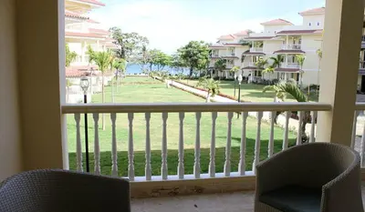 a balcony with two chairs and a view of a park at Cozy and Luxurious 2 bedroom apartment in Sosúa