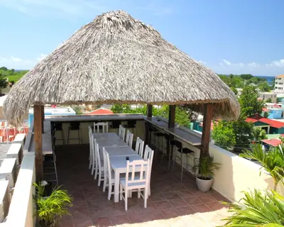 a restaurant with a table and chairs under a thatched roof at Villa Iguana in Bayahibe
