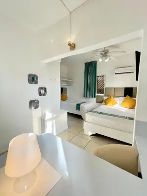 a hotel room with two beds and a desk with a mirror at Villa Iguana in Bayahibe