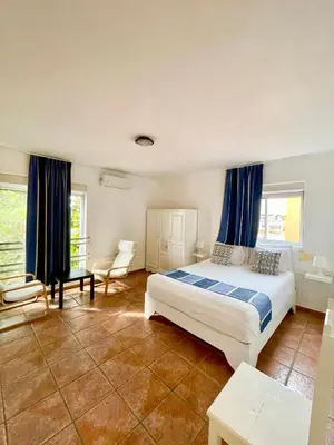 a bedroom with a large bed and blue curtains at Villa Iguana in Bayahibe