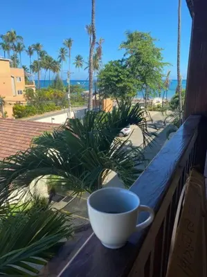 a cup of coffee sitting on a table on a balcony at Las Terrenas beachfront 2 bedrooms condo with pool in Las Terrenas