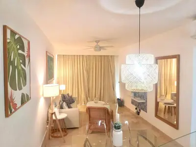 a living room with a glass table and a chandelier at Cana Rock De Lujo 344 Vista Al Campo De Golf in Punta Cana