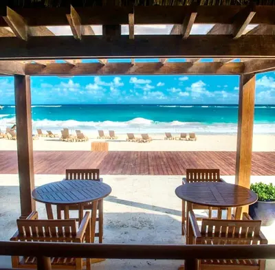 a patio with two tables and chairs and the beach at Cana Rock De Lujo 344 Vista Al Campo De Golf in Punta Cana