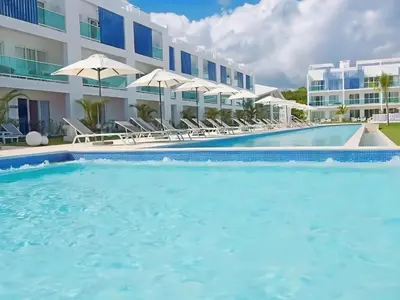 a pool with chairs and umbrellas in front of a hotel at Cana Rock 108 Acceso Directo Piscina Punta Cana in Punta Cana