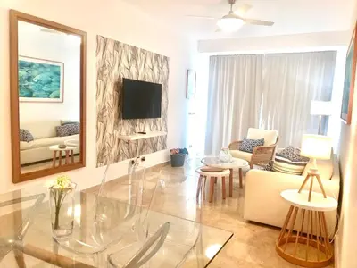 a living room with a glass table and a tv at Cana Rock 351 Impresionante Vista A La Piscina in Punta Cana