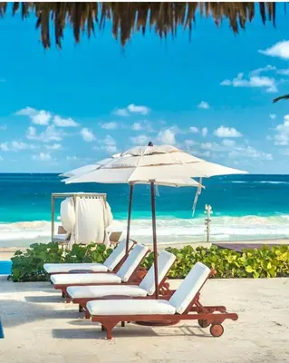 a row of lounge chairs with an umbrella on the beach at Cana Rock 351 Impresionante Vista A La Piscina in Punta Cana