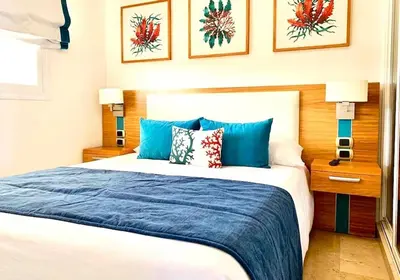 a bedroom with a large bed with blue pillows at Apartamento 120 Jardin Privado Cana Rock in Punta Cana