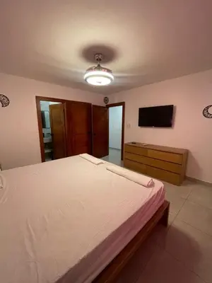 a bedroom with a large bed and a flat screen tv at 3bed Apartment con Terraza y Picsina privada in Santo Domingo