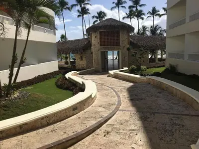 a walkway leading to a building with palm trees at Modern, Welcoming Studio, Ocean View in Juan Dolio in Juan Dolio