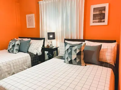 two beds in a room with orange walls at Casa del Arroyo 2-Bedroom Cottage Fireplace and BBQ in Jarabacoa
