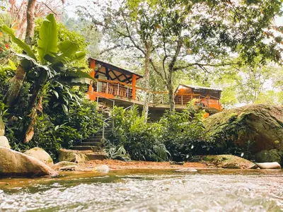 an orange house on the side of a river at Casa del Arroyo 2-Bedroom Cottage Fireplace and BBQ in Jarabacoa