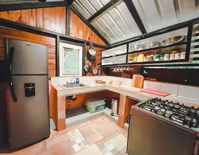 a kitchen with a refrigerator and a sink and a stove at Casa del Arroyo 2-Bedroom Cottage Fireplace and BBQ in Jarabacoa