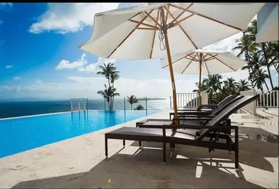 a group of chairs and an umbrella next to a swimming pool at Vista Mare Samana The Best View!! in Santa Bárbara de Samaná