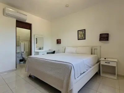 a bedroom with a large white bed and a bathroom at Drake Bolivar Santo Domingo in Santo Domingo