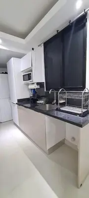 a kitchen with white cabinets and a black counter top at AMG Suites Apartment in Santo Domingo