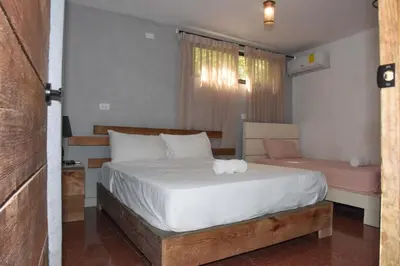 a bedroom with a large white bed and a window at Hostel Gato Colonial in Santo Domingo