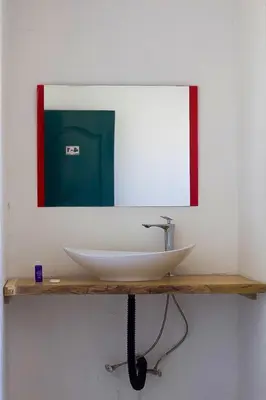 a bathroom with a sink and a mirror on a shelf at Hostel Gato Colonial in Santo Domingo