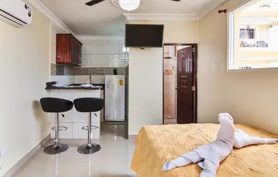 a room with a bed and two stools in a kitchen at Modern Studio Near Airport Fast WiFi Generator in La Viva