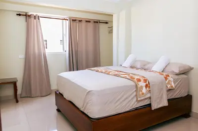 a bedroom with a bed with white sheets and a window at Cozy Apartment Near Airport Wi-Fi & Parking in La Viva