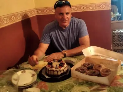 a man sitting at a table with a box of donuts at La casa de Jessica in Santo Domingo
