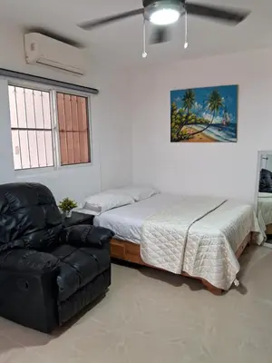 a bedroom with a bed and a black leather chair at Cozy Studios-Private Entrance- HS Internet-AC-Hot Water-Backup Generator-near the Beach in San Felipe de Puerto Plata