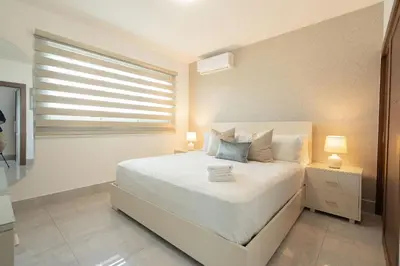 a bedroom with a white bed and a window at Soha suites I in Santiago de los Caballeros