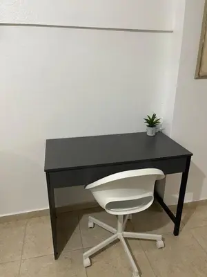 a black desk with a white chair and a plant at Hospedaje de marant 1 in San Felipe de Puerto Plata