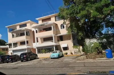 a white building with cars parked in front of it at El más completo, a menos de 5 minutos de la playa, free wifi fuera del alojamiento in San Felipe de Puerto Plata