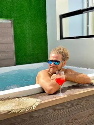 a man laying in a bath tub with a glass of wine at Studio 27 in Santo Domingo