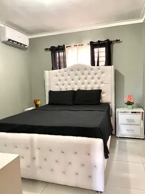 a bedroom with a large white bed with black sheets at Residencial PALMA REAL in Santiago de los Caballeros