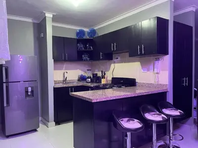 a kitchen with black cabinets and bar stools at Residencial PALMA REAL in Santiago de los Caballeros