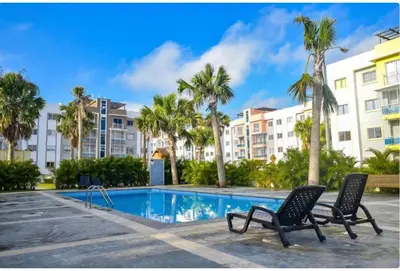 a swimming pool with two chairs and palm trees at Residencial PALMA REAL in Santiago de los Caballeros