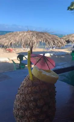 a pineapple with an umbrella on the beach at Mar azul puerto plata in San Felipe de Puerto Plata