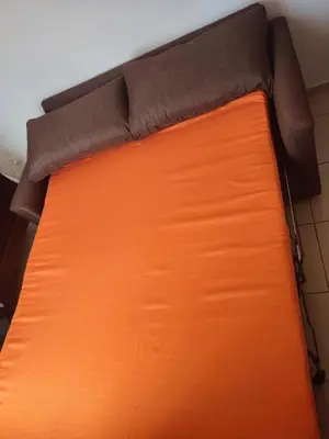 a bed with an orange bedsheet on top of it at Samana house in Santa Bárbara de Samaná