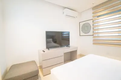 a white room with a television and a chair at SOHA PANORAMA in Santiago de los Caballeros