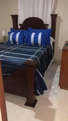 a bed with blue and white pillows on it at Apartamentos Kika in San Felipe de Puerto Plata