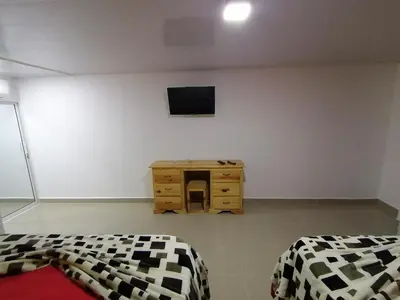 a bedroom with two beds and a desk and a tv at Piscalonga Hotel Restaurant Cozy Family Operated in San Lorenzo de Guayubín