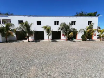 a white building with palm trees in front of it at Piscalonga Hotel Restaurant Cozy Family Operated in San Lorenzo de Guayubín