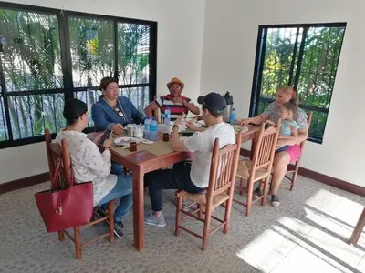 a group of people sitting around a wooden table at Piscalonga Hotel Restaurant Cozy Family Operated in San Lorenzo de Guayubín