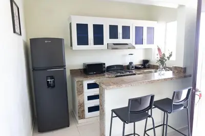 a kitchen with a refrigerator and two bar stools at Gaviota Paradise in La Romana