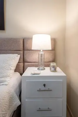 a white nightstand with a lamp on it next to a bed at Acogedor estudio 7 en la Zona Colonial in Santo Domingo