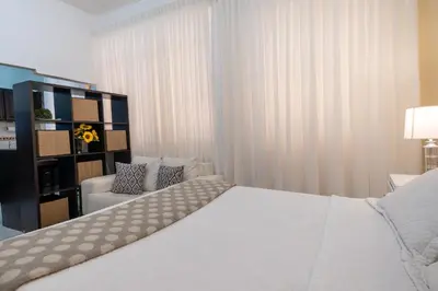 a bedroom with a white bed and a chair at Acogedor estudio 7 en la Zona Colonial in Santo Domingo