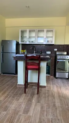 a kitchen with a red chair at a kitchen counter at Hotel María Bonita Higüey, Apartments in Higuey