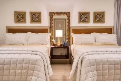 a bedroom with two beds and a table with a lamp at Naranjo Hotel Boutique in Higuey