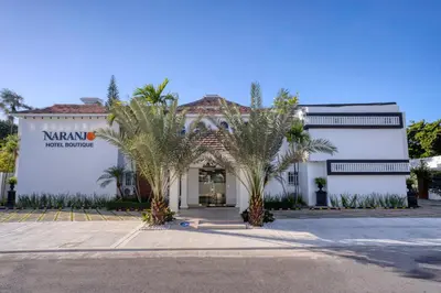 a white building with palm trees in front of it at Naranjo Hotel Boutique in Higuey
