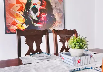 a dining room table with a painting of a clown at Exclusive 3 BDR, Gym & Pool, SeaView, Luxury Tower in Santo Domingo
