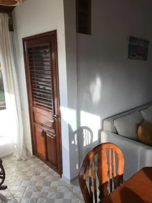 a living room with a couch and a wooden door at La Cortesana Cozy Apt Steps to the Beach in Las Terrenas